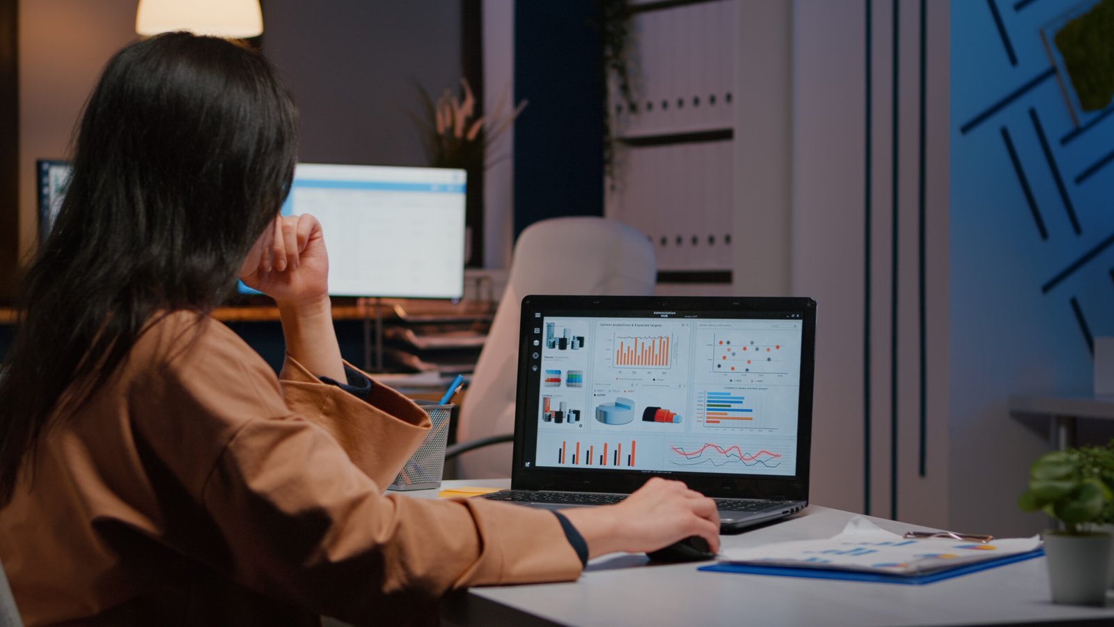 Overworked businesswoman typing financial statistics on laptop sitting at desk